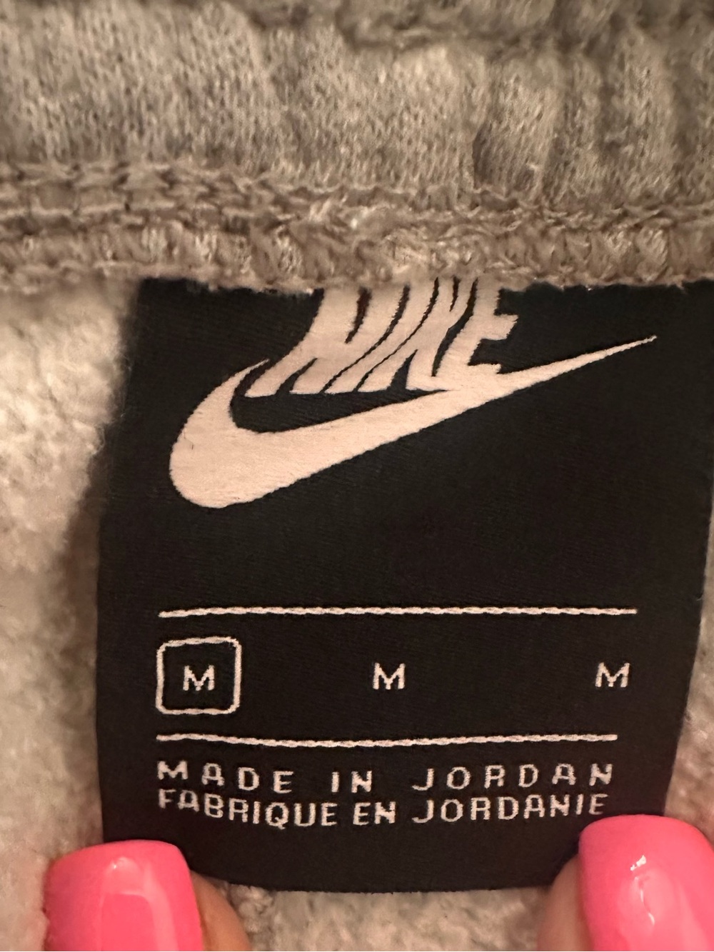 Nike Black Tag with White Swoosh on Grey Fabric